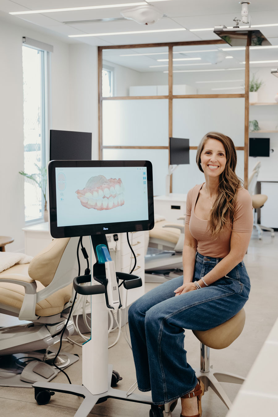Dr. Amanda Vanderstelt beside an iTero 3D scanner showing a digital scan of a patient's teeth at her Denver orthodontic office