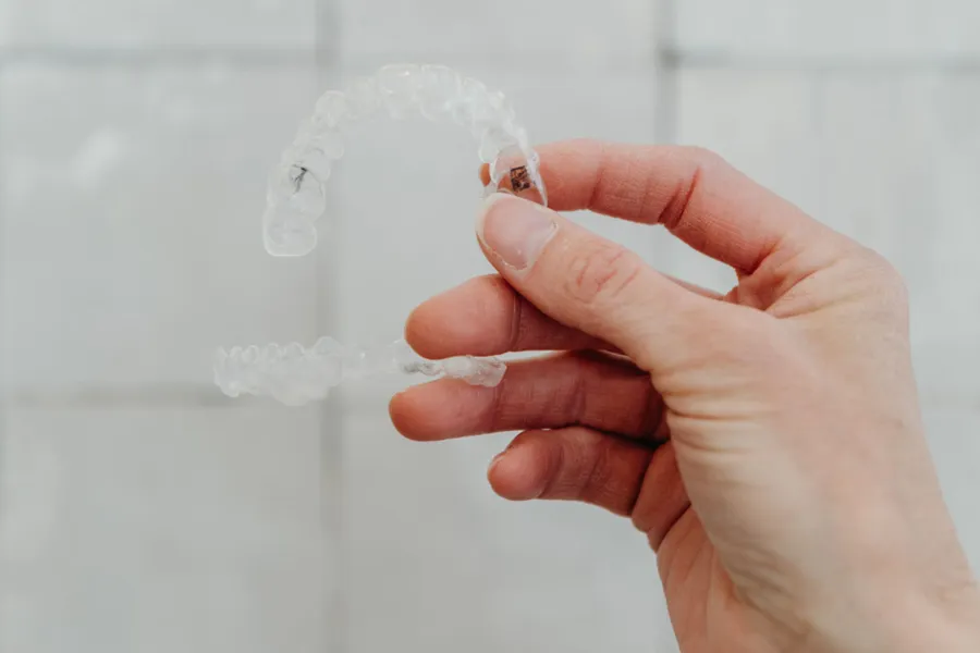 Hand holding a clear aligner tray at aligned. Orthodontics in Denver