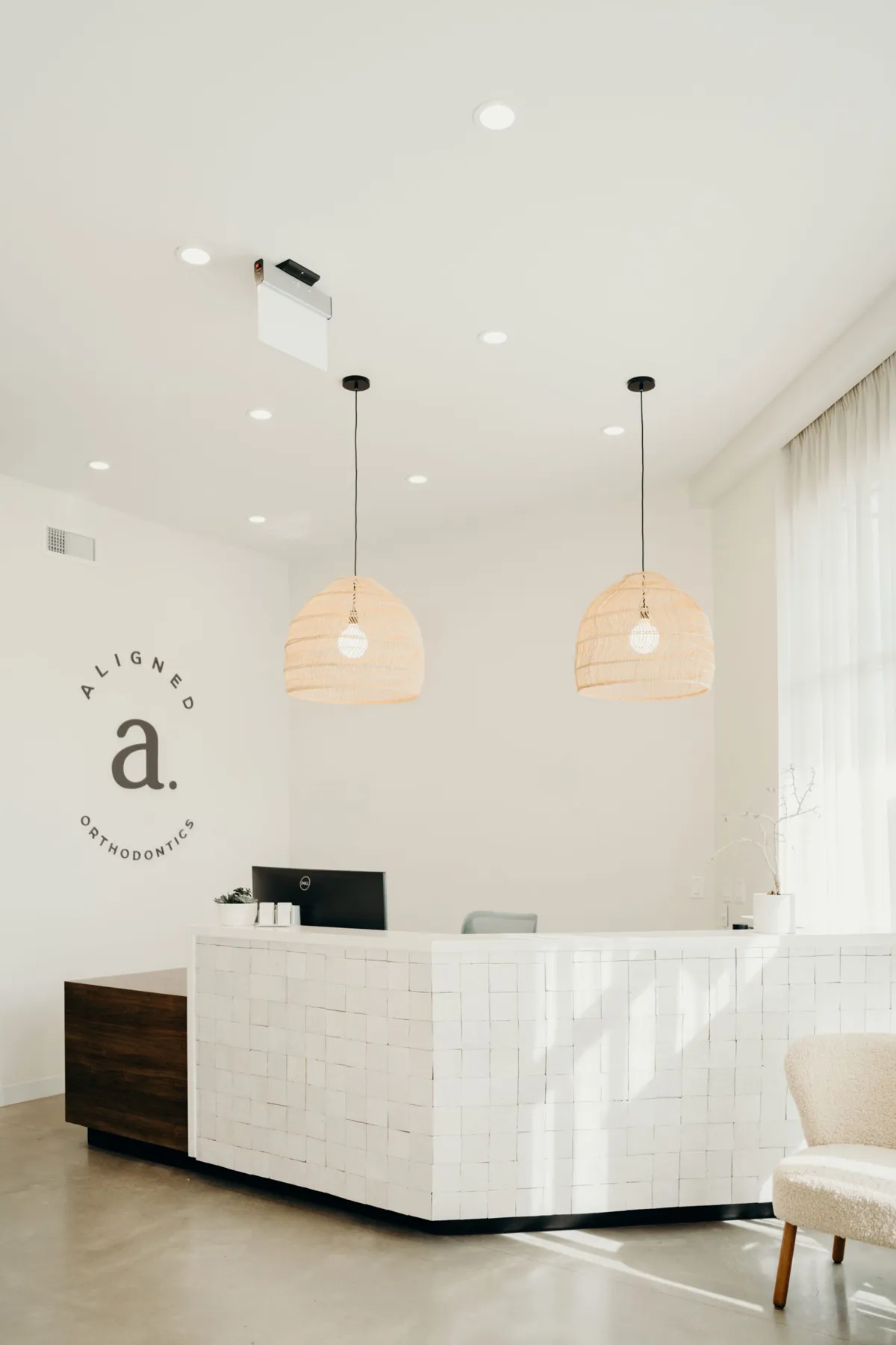 Front desk under woven pendant lights at aligned. Orthodontics in Denver