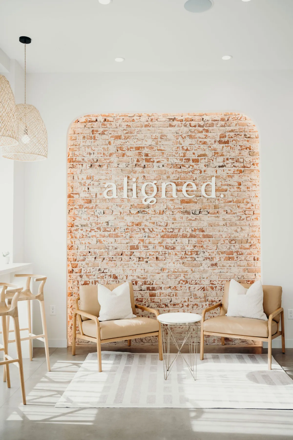 Waiting area with two armchairs in front of the brick aligned. sign wall at the Platt Park orthodontic office